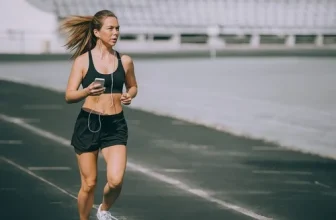 Joggeuse qui court sur une piste d’athlétisme, tel à la main, sans accessoire de rangement.